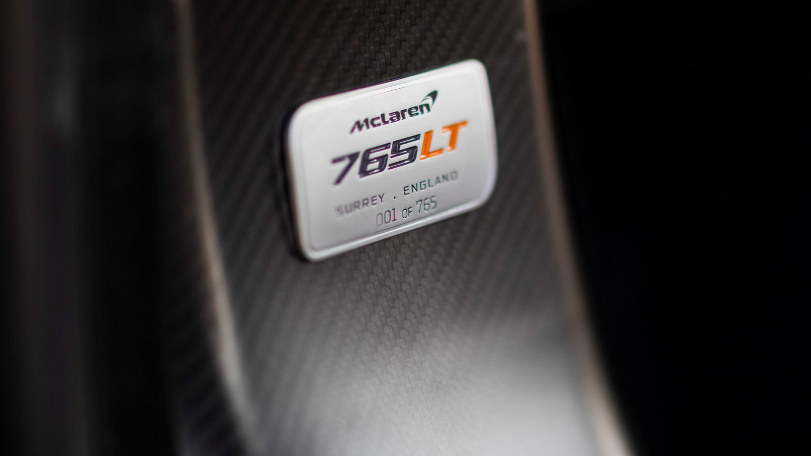 McLaren 765LT nameplate on carbon fiber panel, engraved with '001 of 765, highlighting its limited production and exclusivity