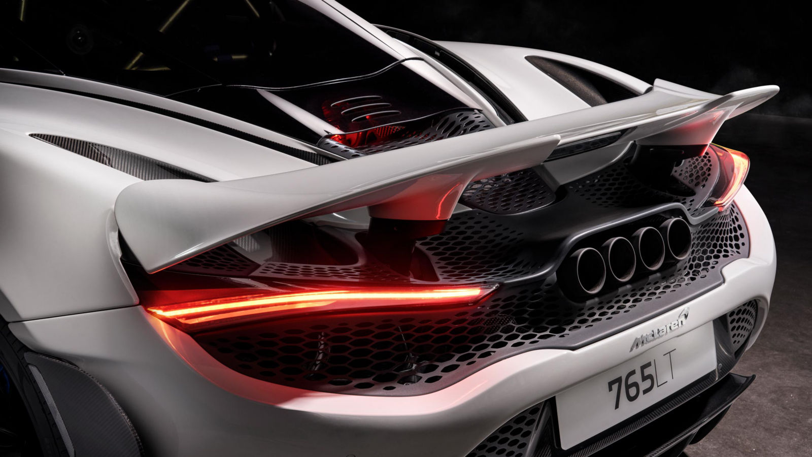 McLaren 765LT rear view in white, featuring an active rear wing, quad exhaust system and aggressive track styling