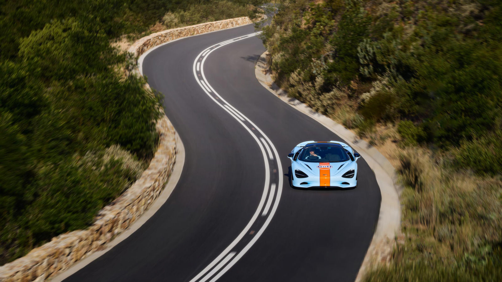 The McLaren and Gulf collab supercar driving at speed along a cliff top.