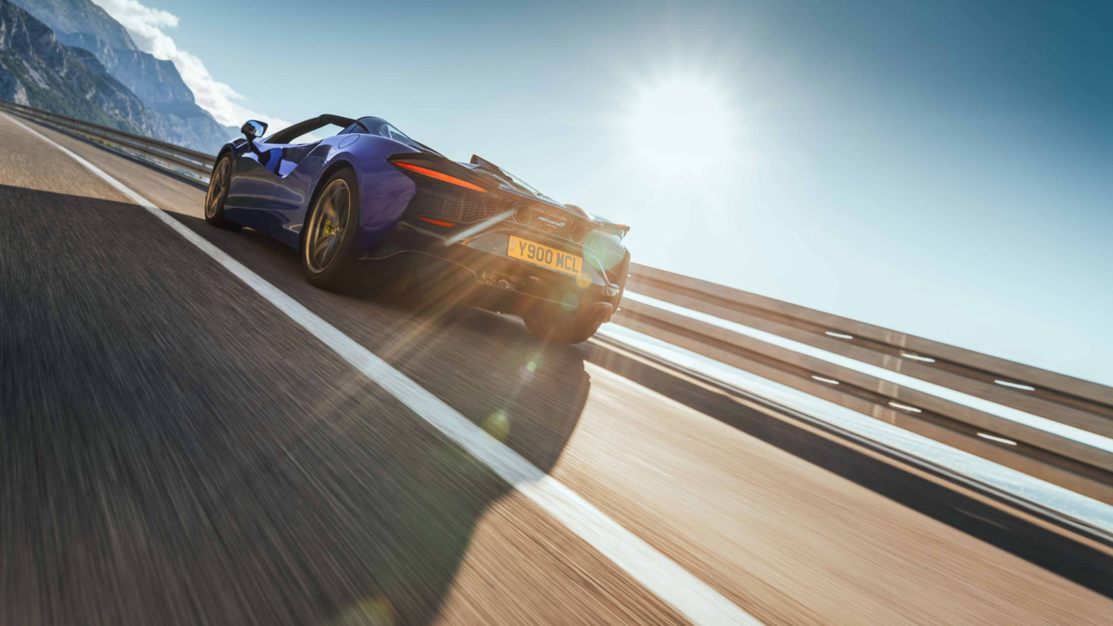 Shot of the back of the McLaren Artura in blue driving at speed.