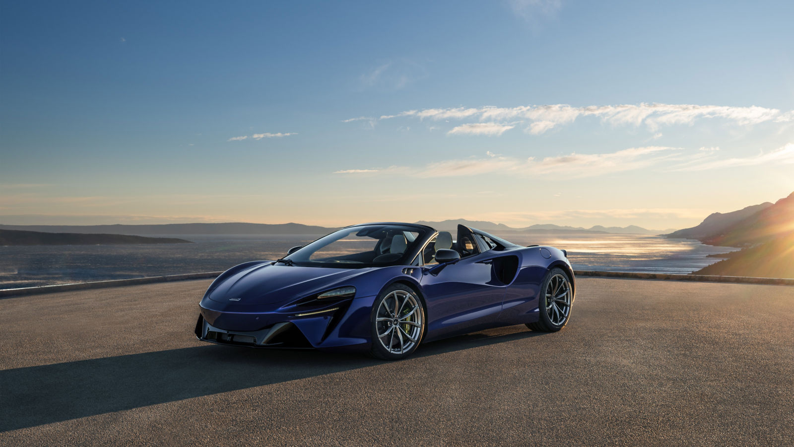 Shot of the McLaren Artura parked facing away from a cliff top view of the ocean.