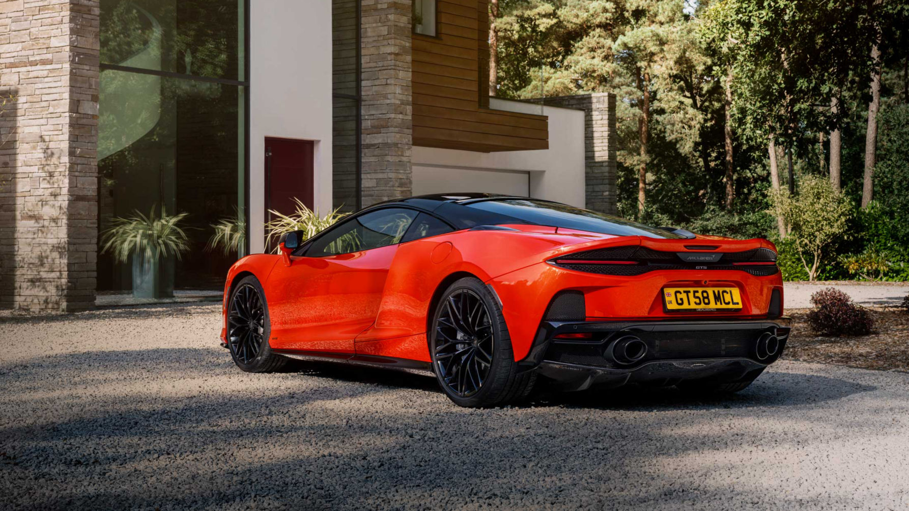 Shot of the back of the McLaren GTS in red parked on a stoney driveway.