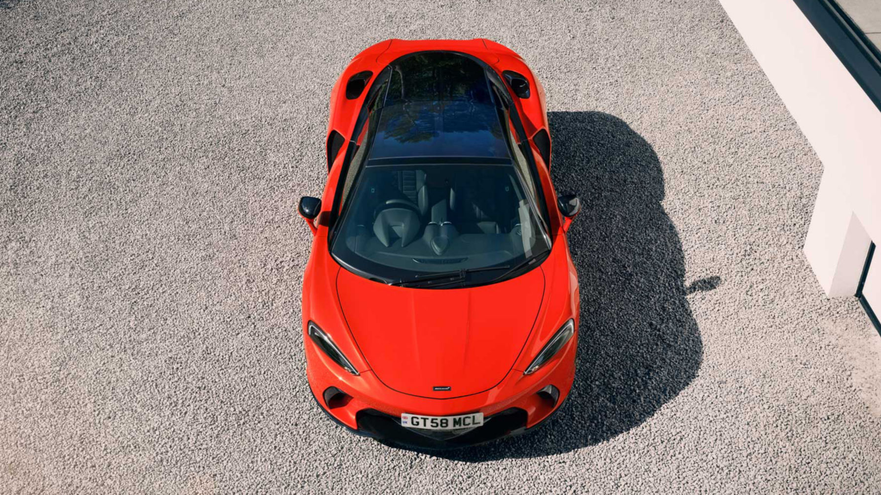 Birds eye view shot of the McLaren GTS in red parked on a stoney driveway.