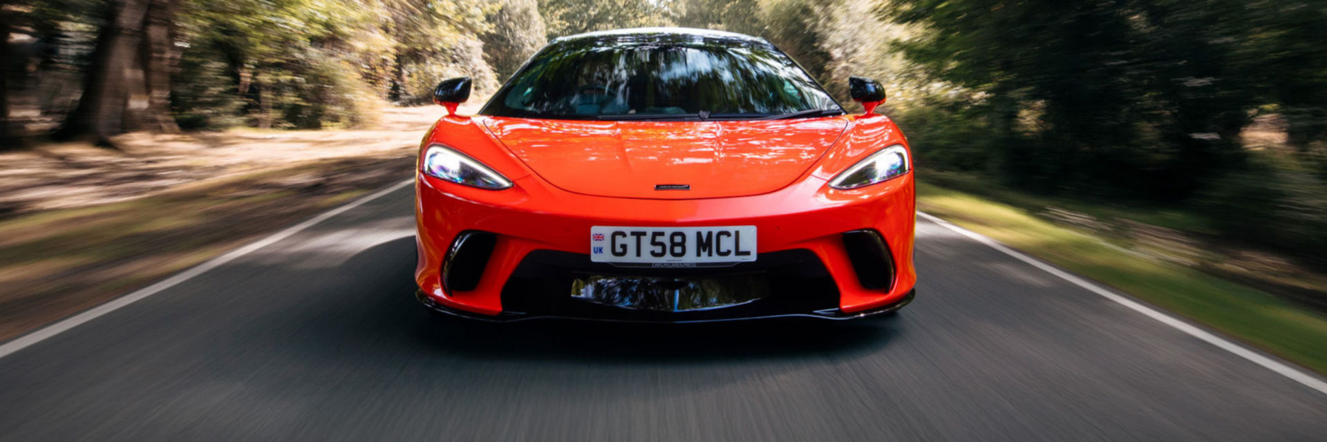 The McLaren GTS driving at speed along a country road.