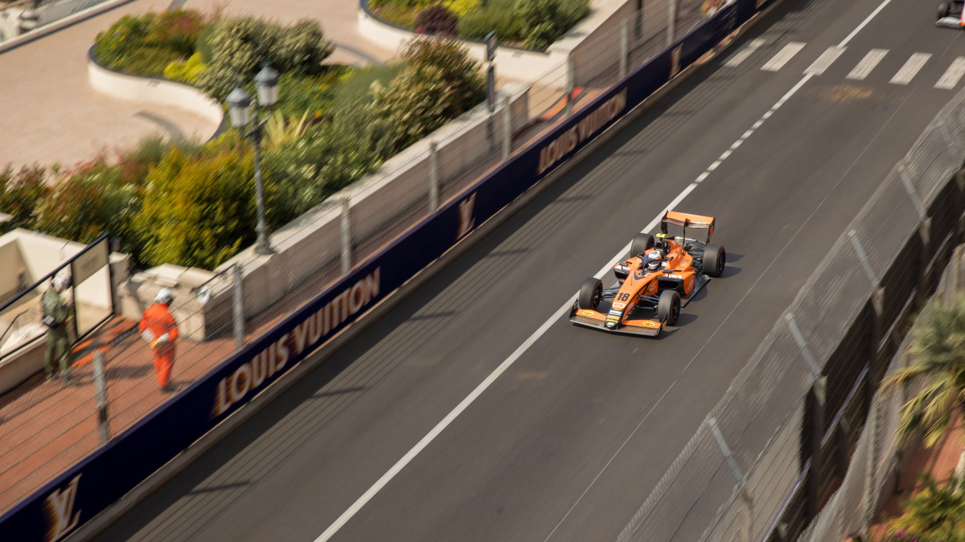 McLaren F1 car driving at speed along Monaco road.