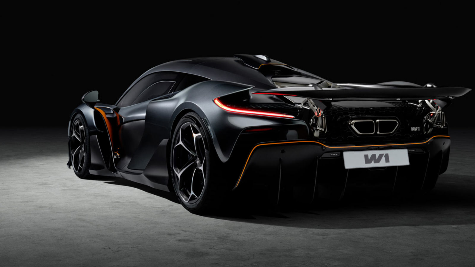 Black McLaren W1 in the shadows with a soft spot light exposing the rear and side detail of the hypercar