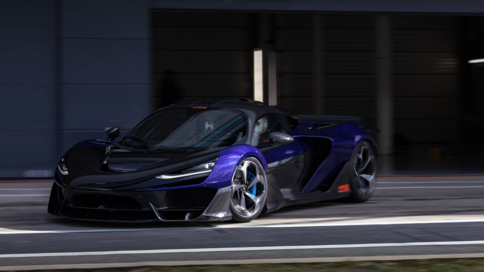 A three quater shot of the front of a McLaren W1 slowly exiting the pit lane of the Silverstone track.