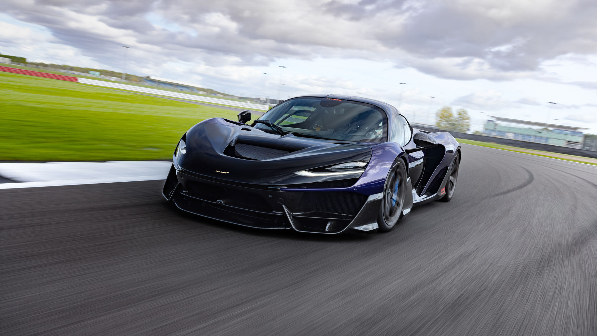 The McLaren W1 in black driving at speed around a bend at the Silverstone track.