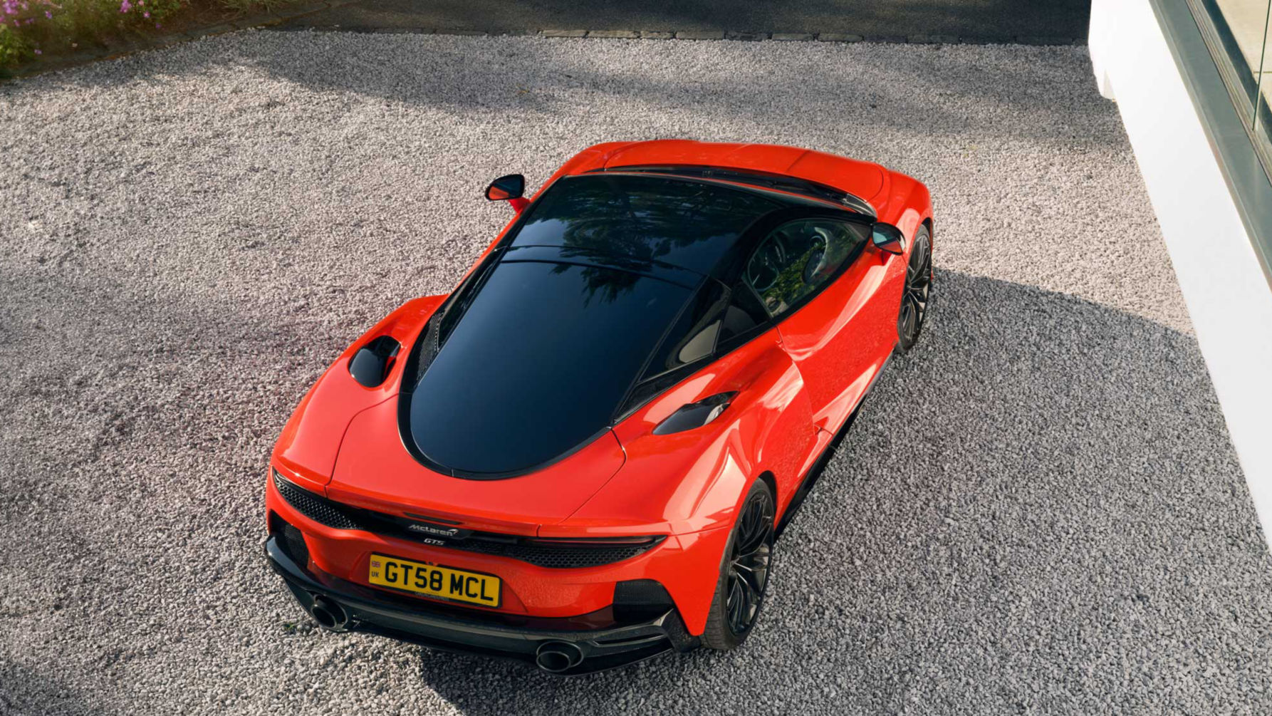 High view shot of the McLaren GTS in red parked on a stoney driveway.