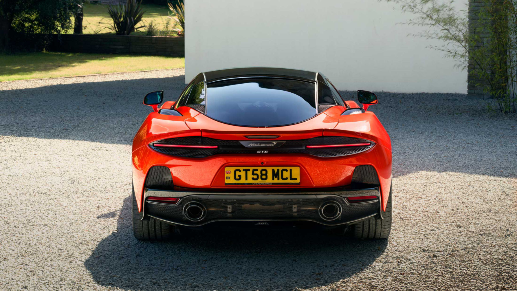 Shot of the rear of the McLaren GTS in red parked on a stoney driveway.