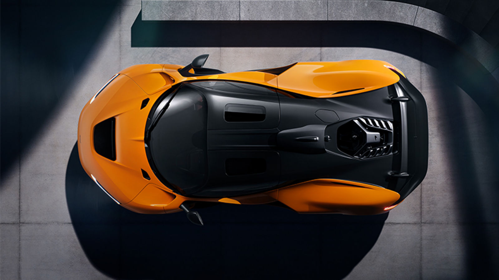 A high aerial shot of an orange McLaren W1, with a concrete perimeter showing the car from above.